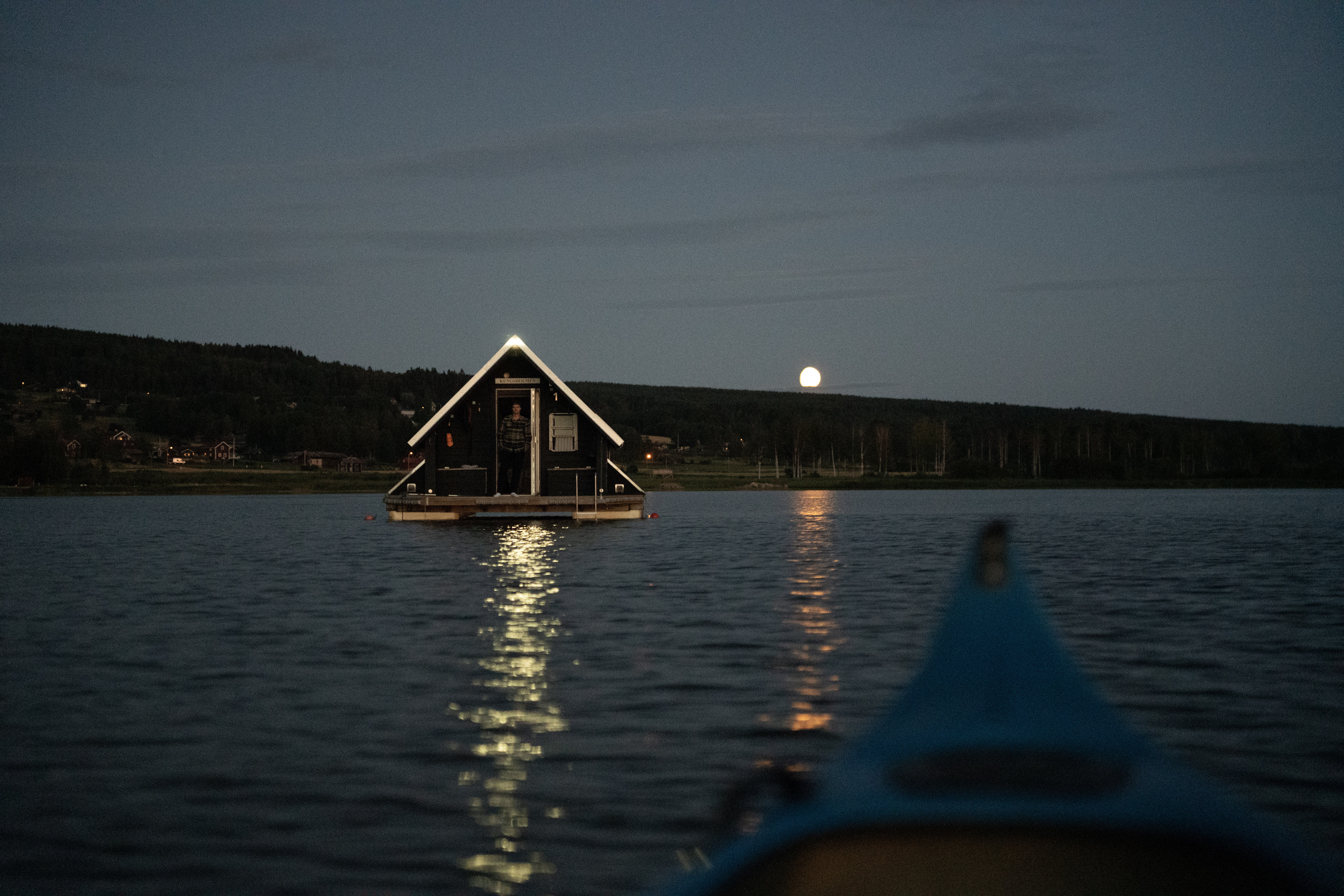 Det upplysta flytande hotellrummet på Orsasjön en kväll, sett från kanoten